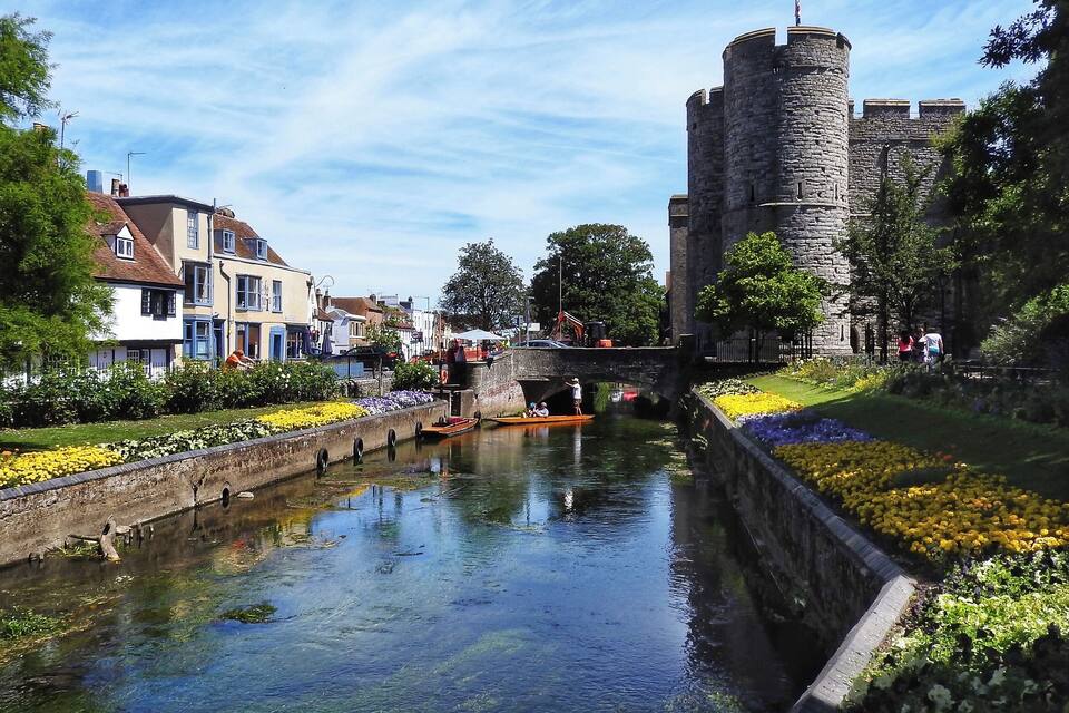 A canal with a castle and colorful flower beds.