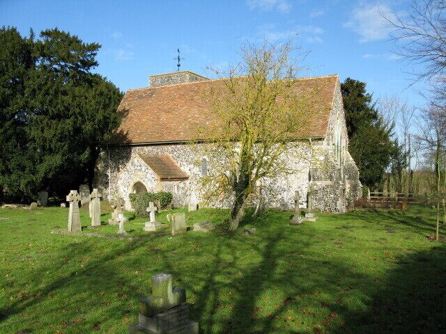 A stone church with a tiled roof, surrounded by a cemetery with headstones.