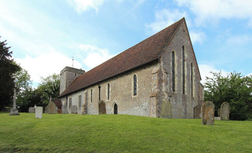 A historic church with a steeply pitched roof, arched windows, and a stone tower.