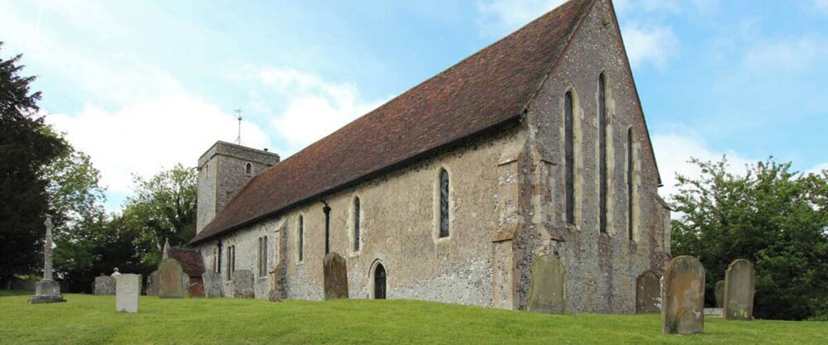 A historic church with a steeply pitched roof, arched windows, and a stone tower.