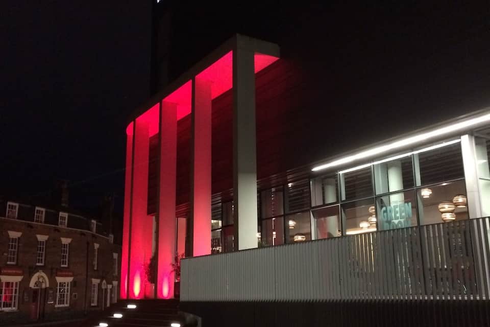 Un edifici modern amb il·luminació vermella i un rètol que diu “The Green Room”.