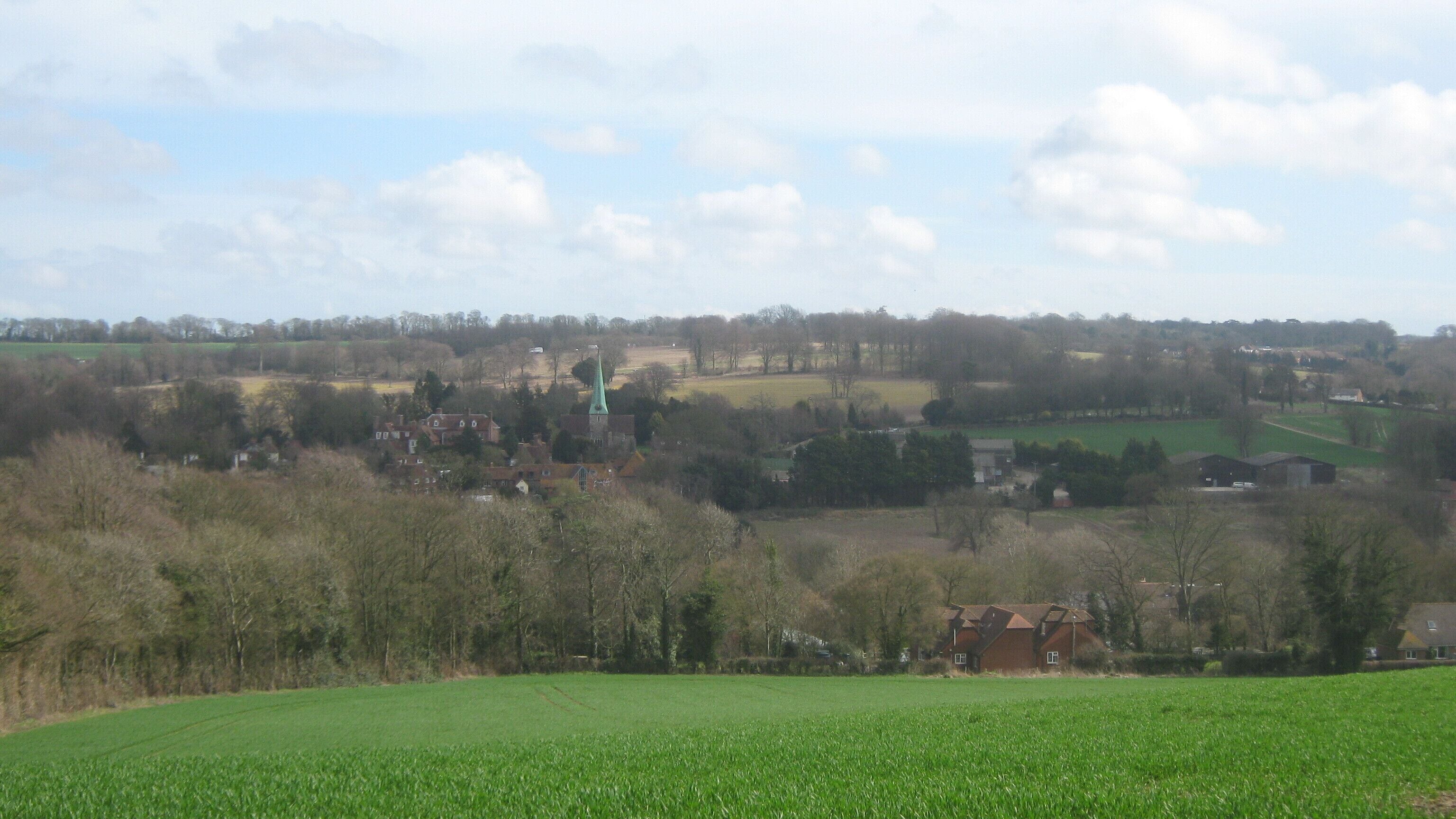View of Barham Seen from Greenhills, near Greenhills Farm. Behind the Barham Church spire, a few cars on the A2 Dual carriageway can just be seen in the background.