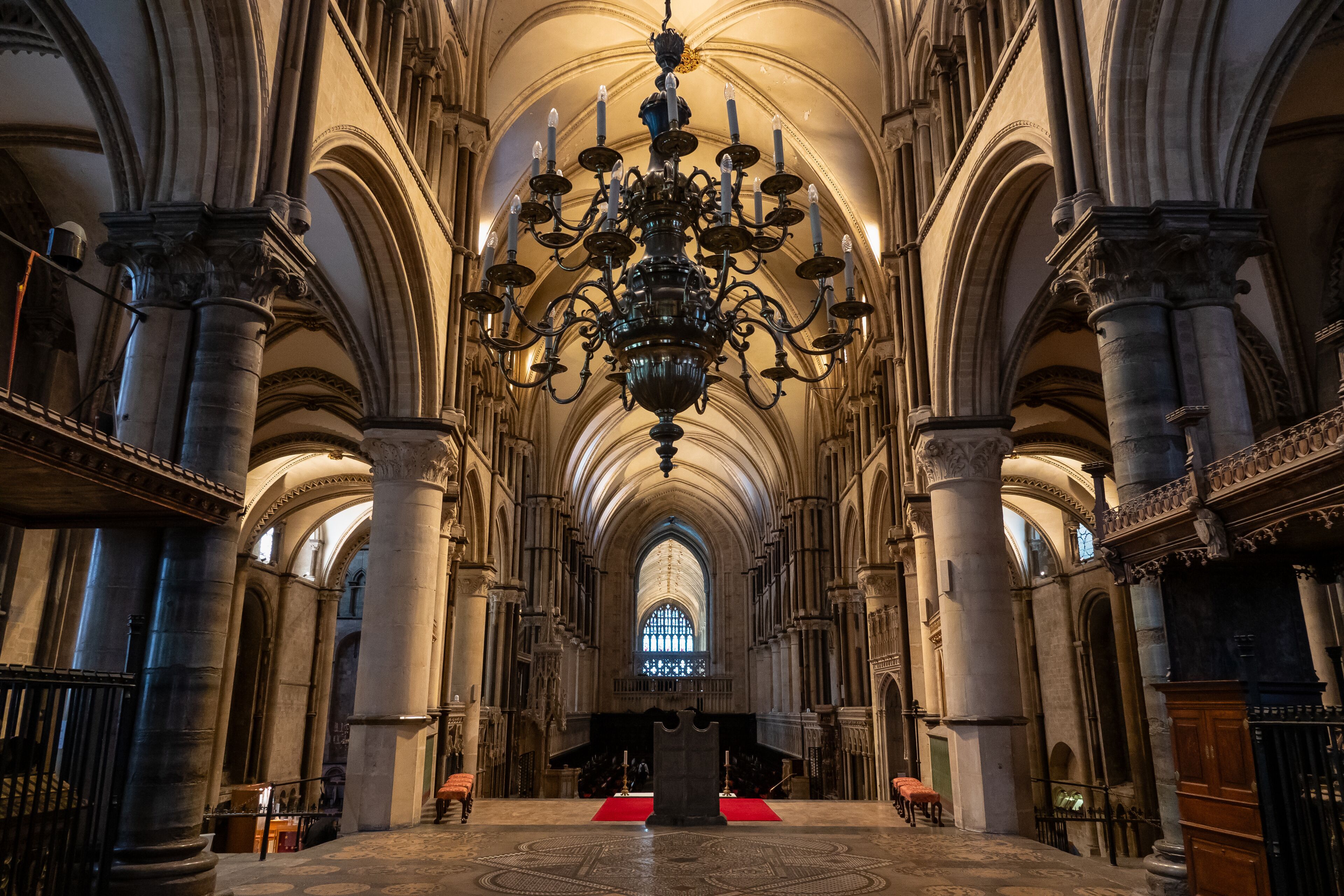 A grand cathedral interior with a large chandelier, arched ceilings, and a central altar.
