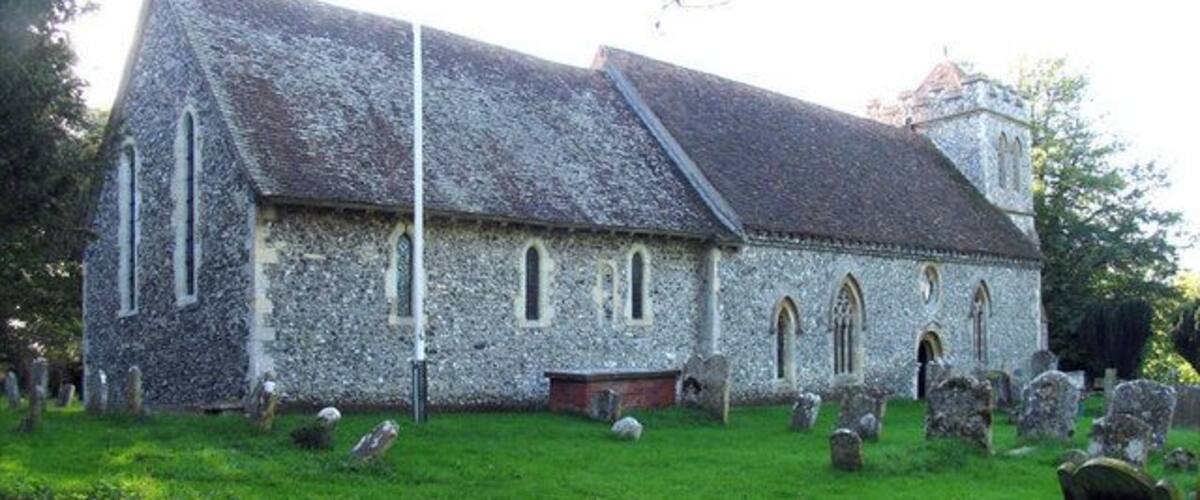 A stone church with a steeple, surrounded by a cemetery with headstones.