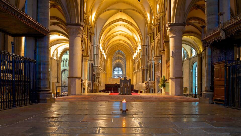 A cathedral interior with high vaulted ceilings, large stone columns, and a central aisle leading to an altar.