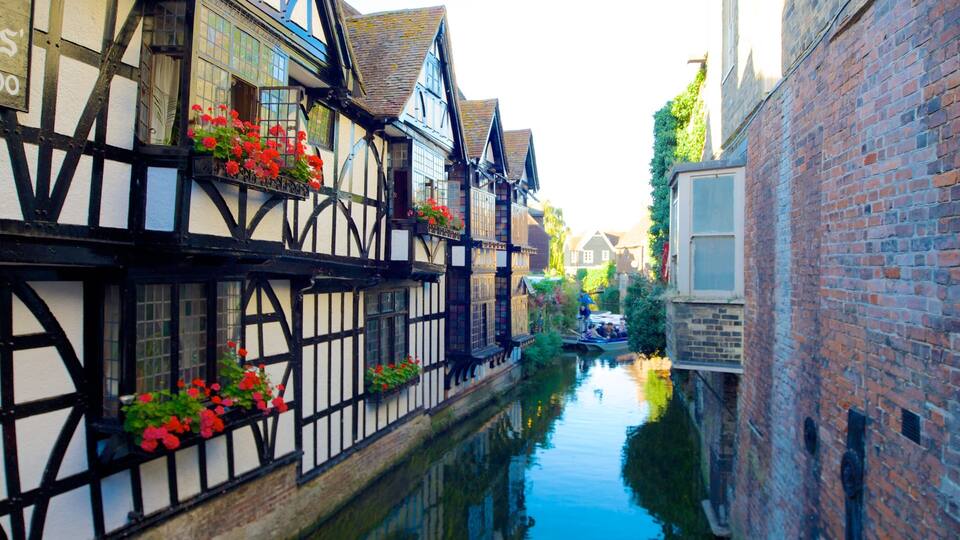 A narrow waterway flanked by traditional timber-framed buildings with flower boxes.
