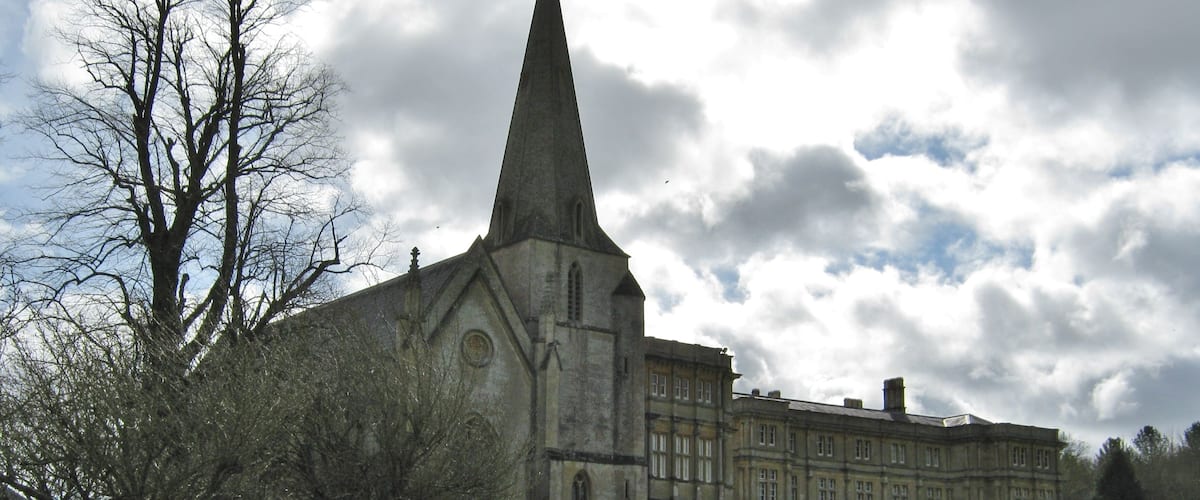 A large church with a tall spire, surrounded by a well-maintained lawn and trees.