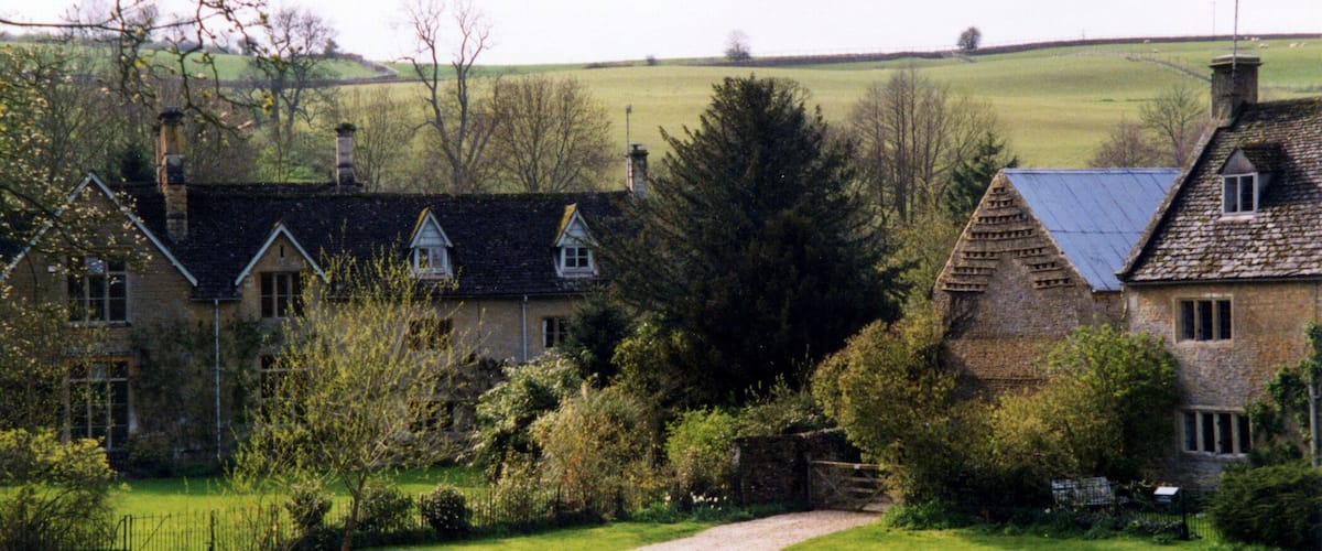 A rural landscape with stone houses, a winding path, and a river.