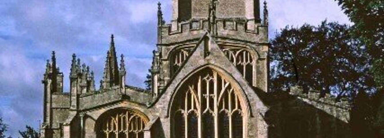 Una iglesia de estilo gótico con una alta torre y amplios ventanales apuntados.