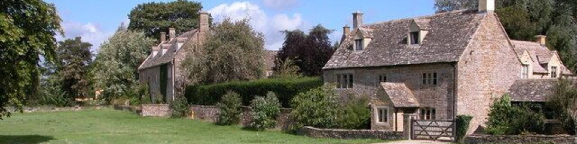 A stone house with a grassy field in front.