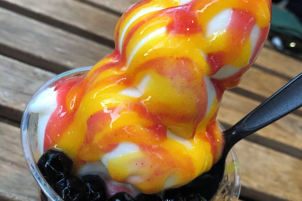 A bowl of colorful dessert with black tapioca pearls.