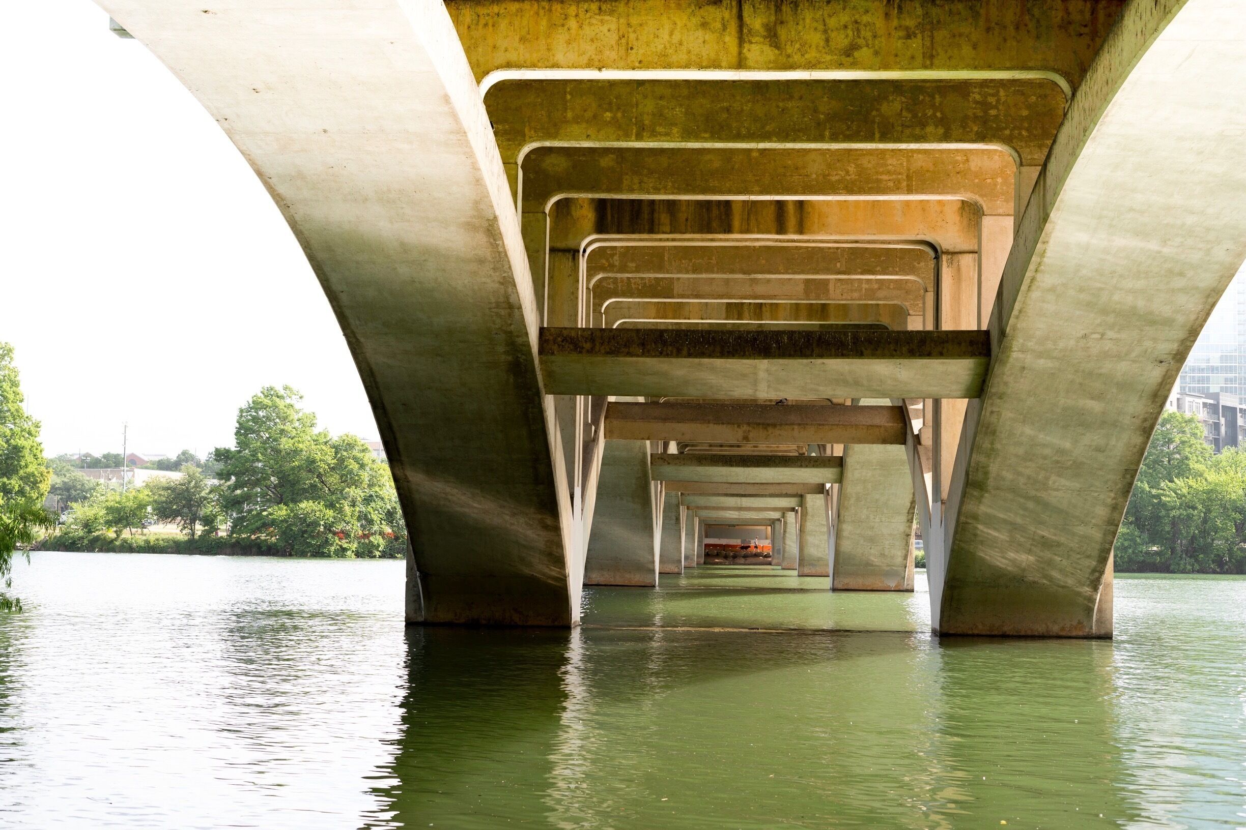 A concrete bridge over a body of water with greenery in the background.