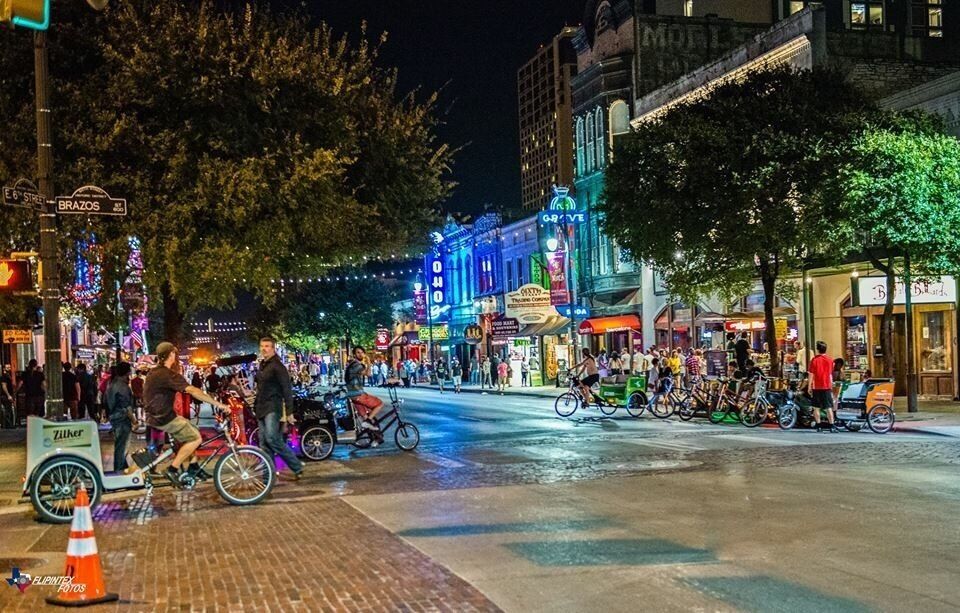 Una calle iluminada con edificios coloridos y una multitud de gente.