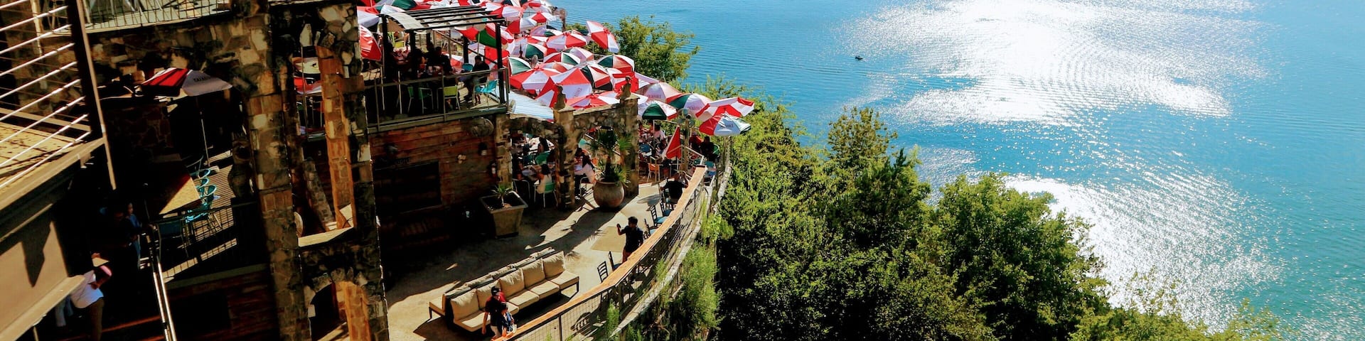 A waterfront restaurant with outdoor seating overlooking a large body of water.
