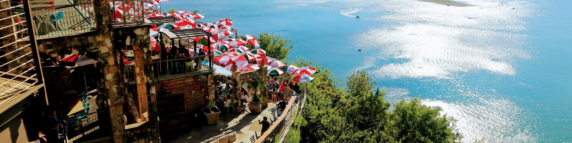 Restaurante à beira-mar com área externa e vista para uma grande extensão de água.