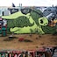Une grande fresque murale représentant une créature verte avec un grand œil, peinte sur un mur.