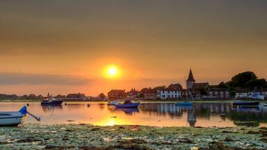 Summer sunset over Bosham Harbour and village with the church spire of Holy Trinity Church, West Sussex, UK