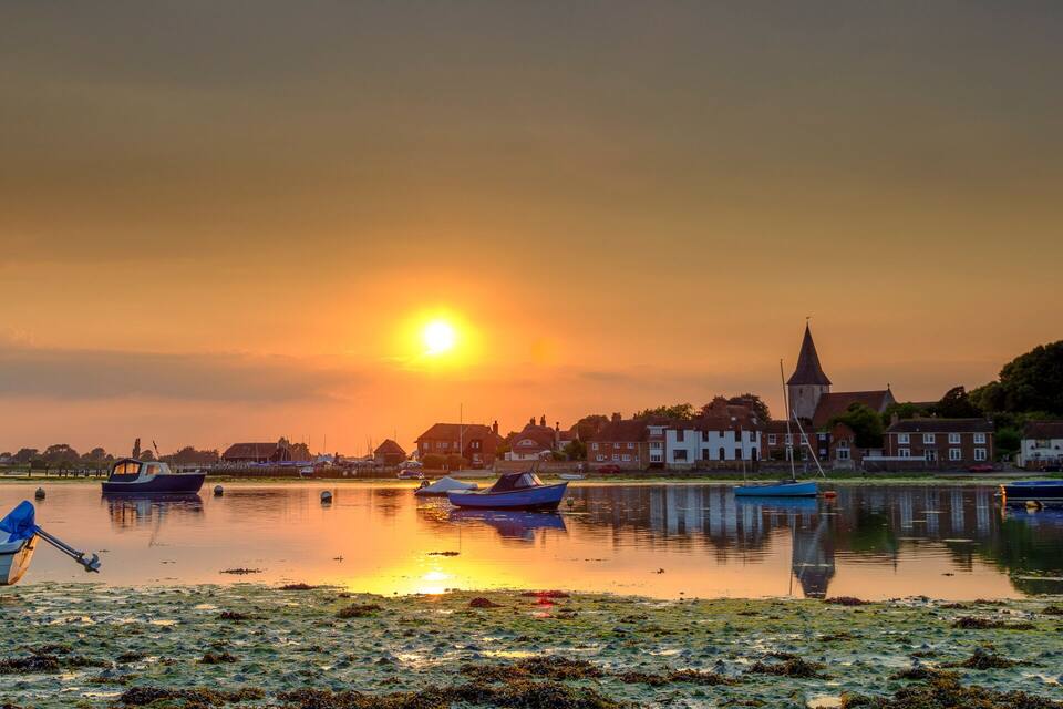 A sunset over a calm lake with boats and houses along the shore.