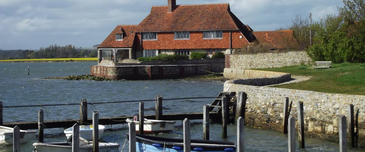 A house by a lake with boats docked in the foreground.