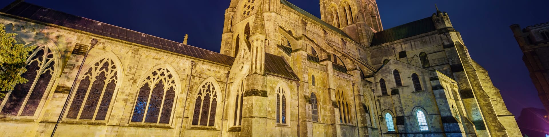A historic cathedral with pointed arches and a tall spire, illuminated at night.