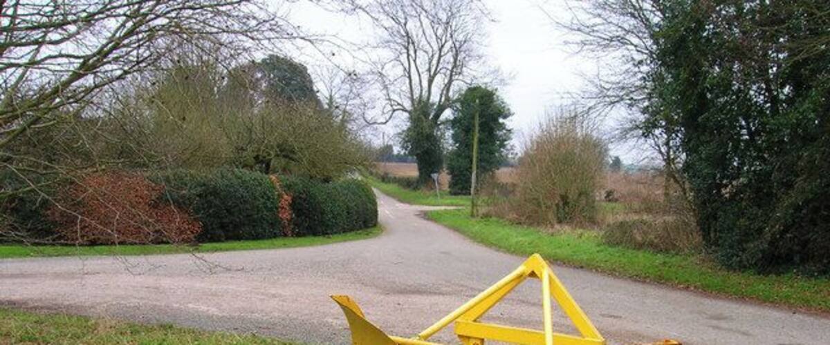 A rural road with a yellow metal structure on the side.
