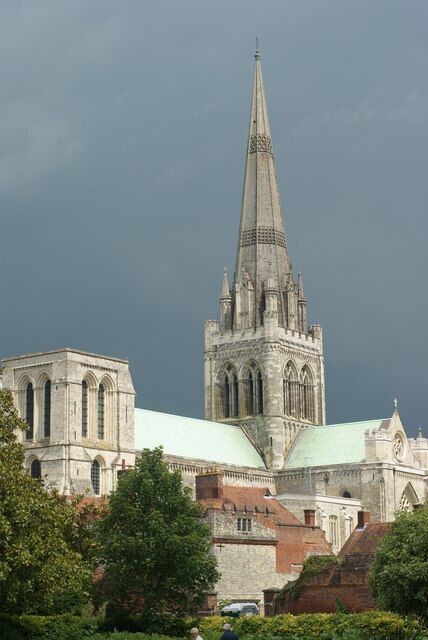 A Gothic cathedral with a tall spire, surrounded by trees and other buildings.