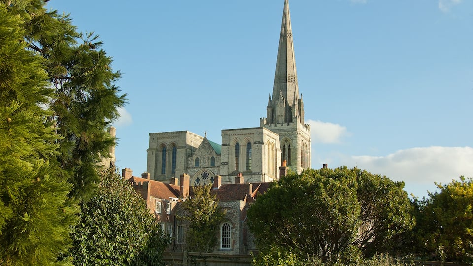 A historic church with a tall spire, surrounded by lush greenery.