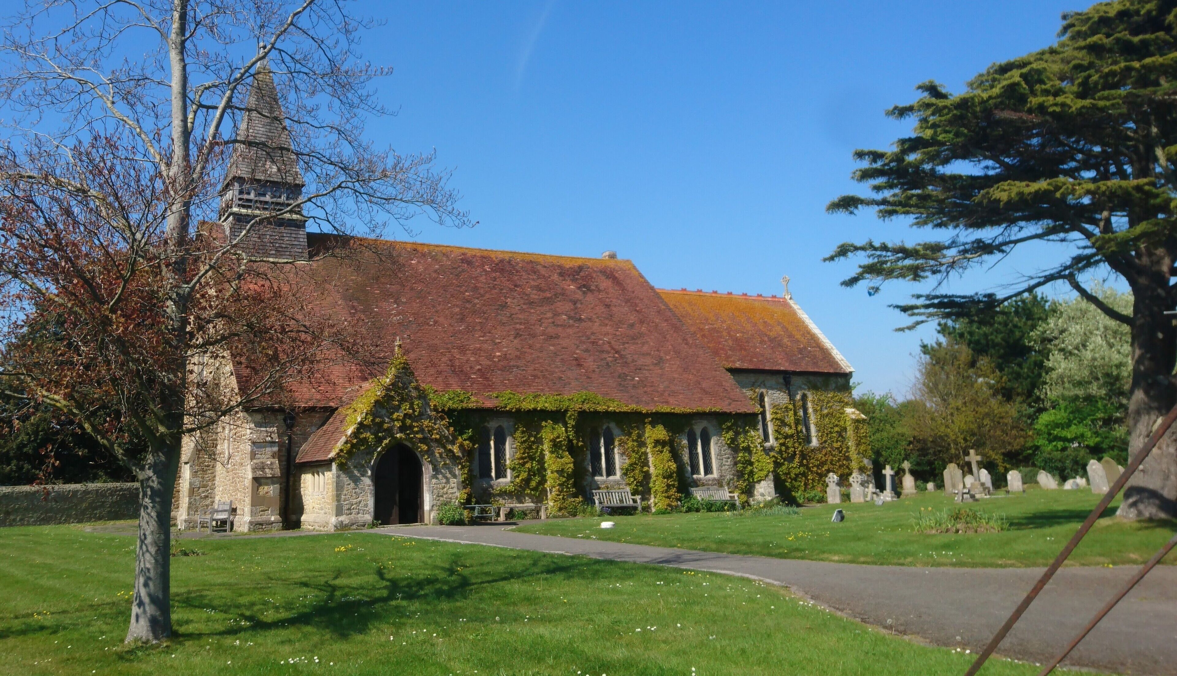 A church with a red-tiled roof, ivy-covered walls, and a stone tower.