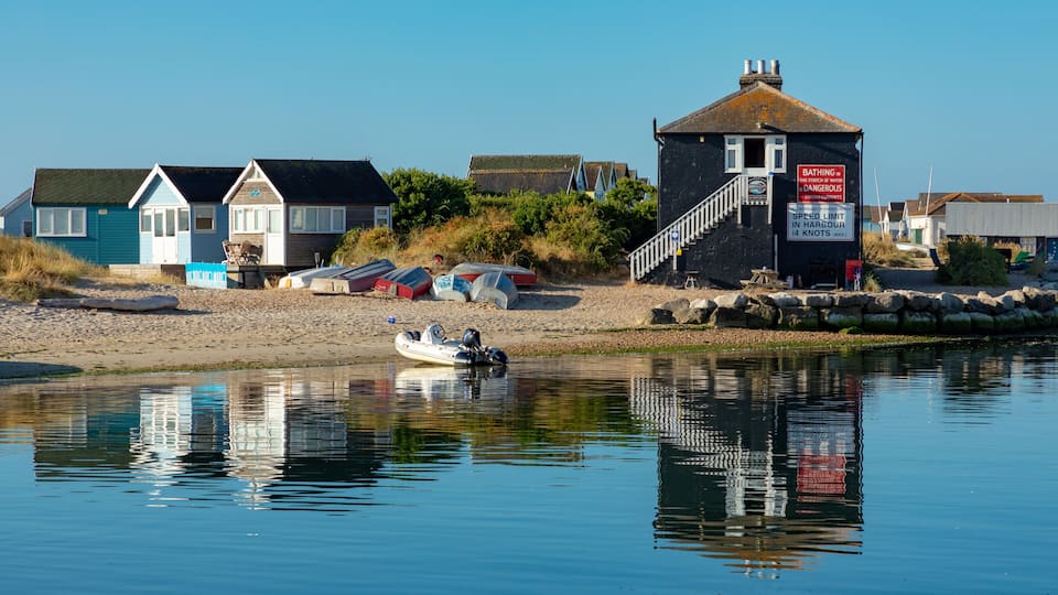A coastal village with houses, a lighthouse, and boats on the shore.