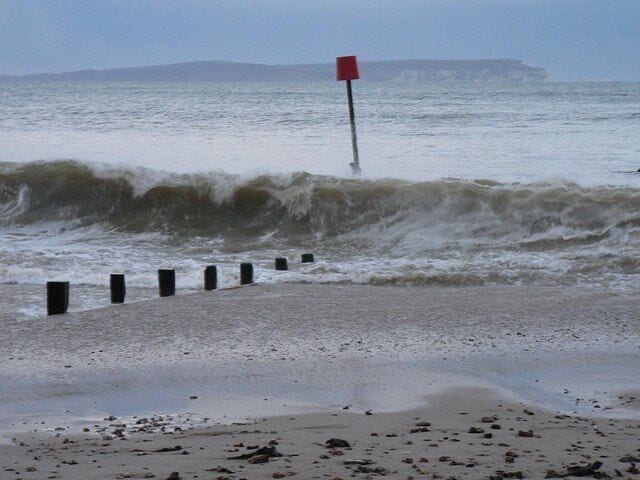 Waves, groynes and lighthouse view Looking across the Solent on this windy afternoon, the red light of the Needles lighthouse can just be discerned far right of picture.
