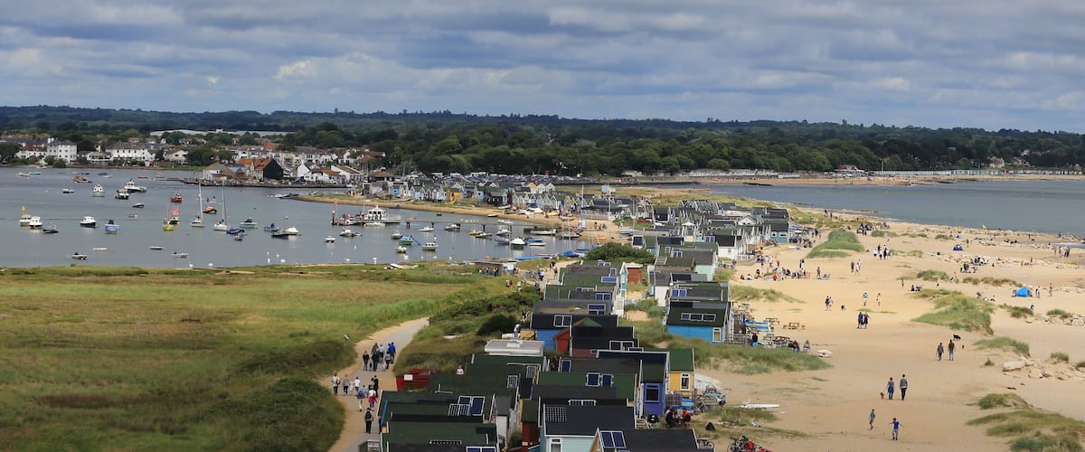A coastal town with a sandy beach, a marina with boats, and houses along the shore.