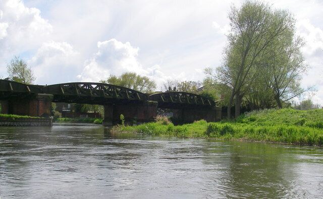 A river with a bridge, greenery, and a tree.