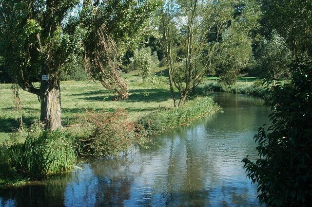 A calm river with trees and grassy banks.