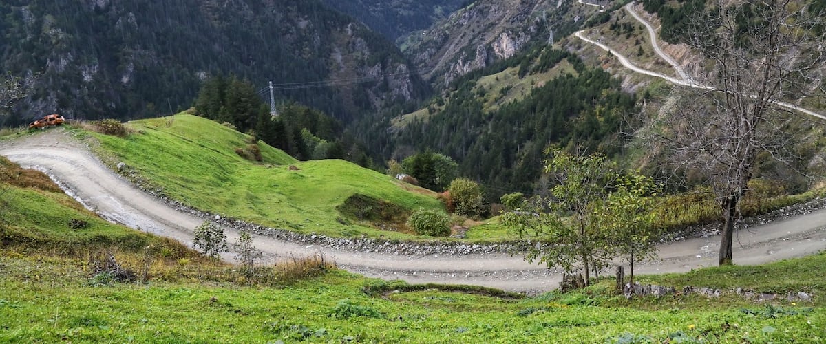 A mountainous landscape with a winding road, green hills, and a valley.