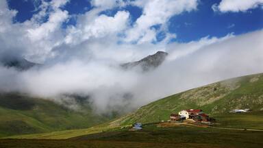 A mountainous landscape with a house and a path.