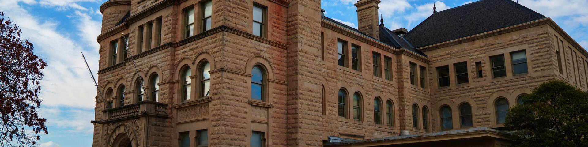 A large, historic stone building with a prominent tower and arched windows.