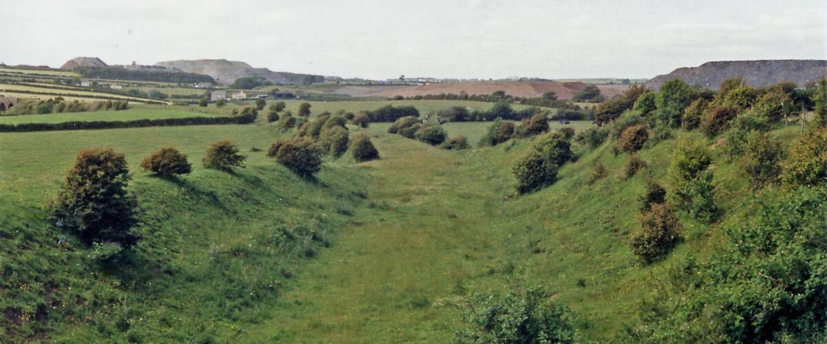 Rolling hills, a river, and distant buildings.