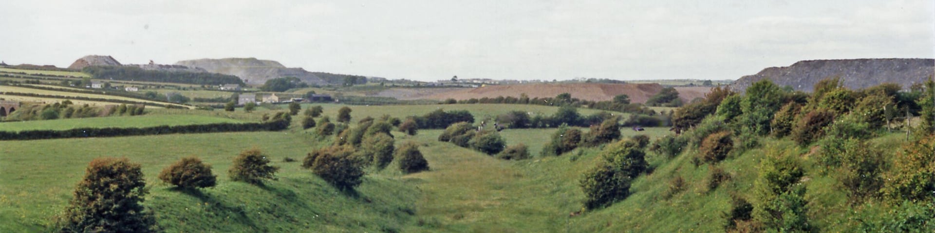 Rolling hills, a river, and distant buildings.