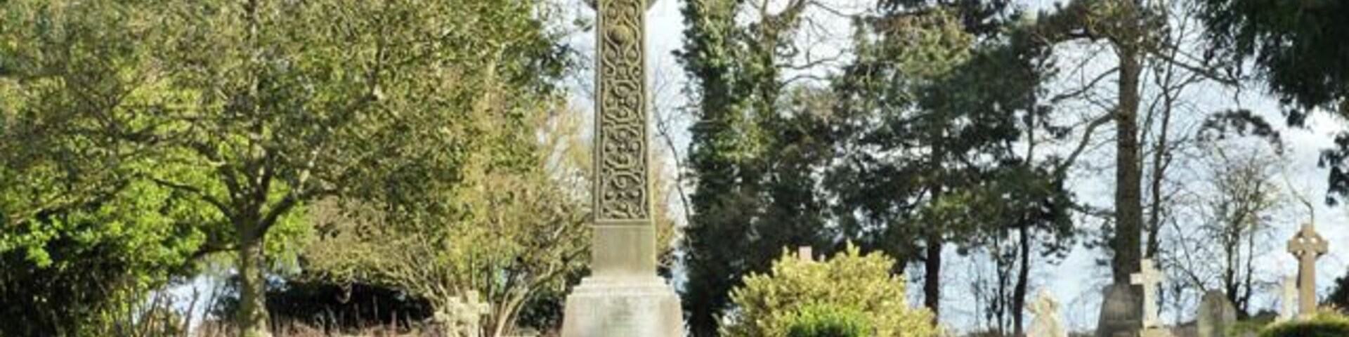 Un cementerio con una cruz celta destacada y lápidas de piedra.