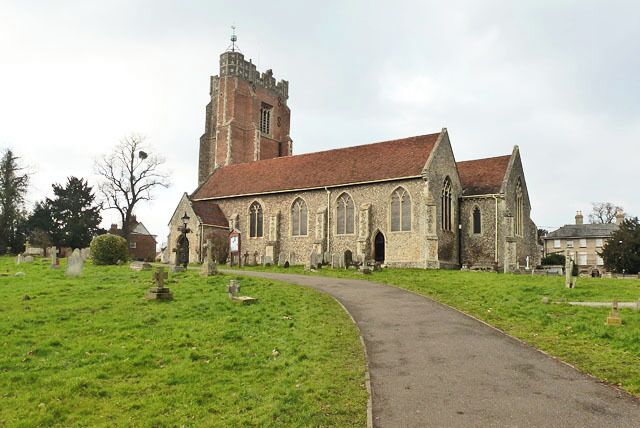 A church with a tall tower and a paved path leading to it.