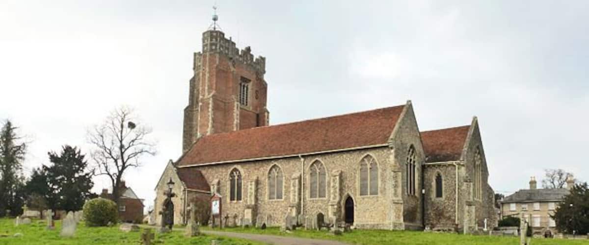A church with a tall tower and a paved path leading to it.