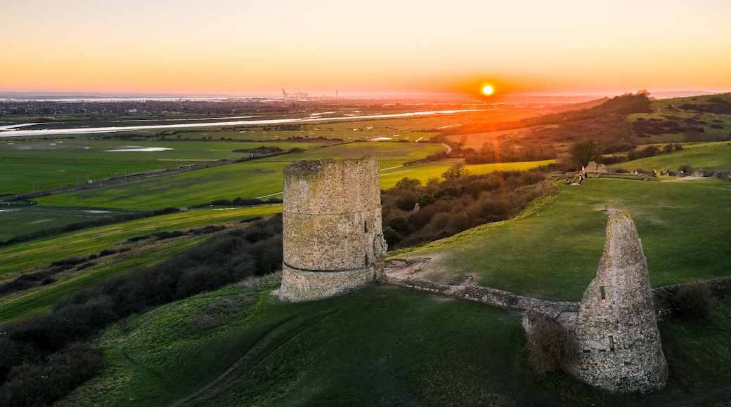 A sunset over a landscape with two stone towers and a river.