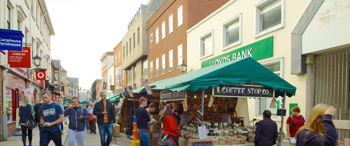 A street market with a coffee stand and a Lloyds Bank building.