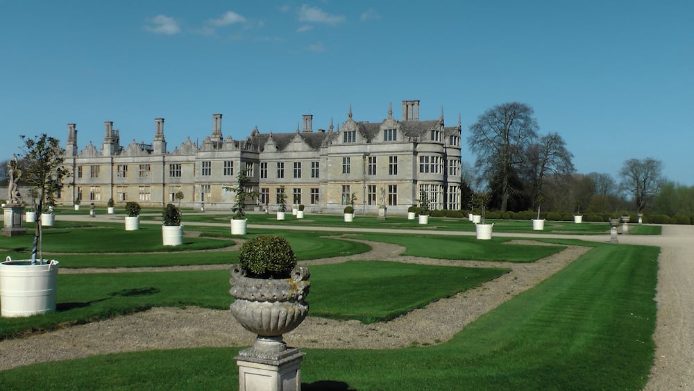 Un magnifique bâtiment historique, doté de jardins symétriques et surplombé d’un ciel d’un bleu éclatant.