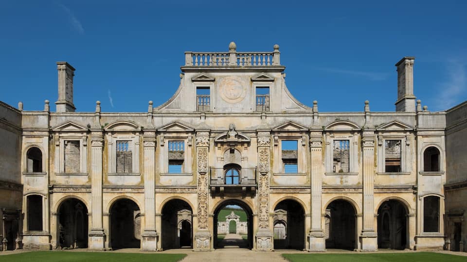 A historic building with a central archway, symmetrical facade, and a clock tower.