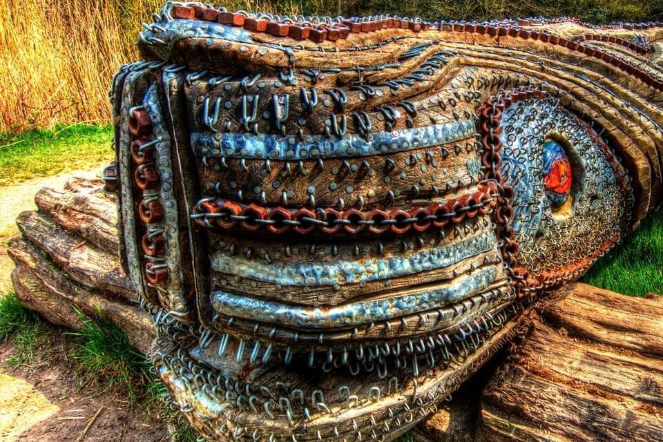 A large, intricately decorated log with chains and metal elements, set in a wooded area.