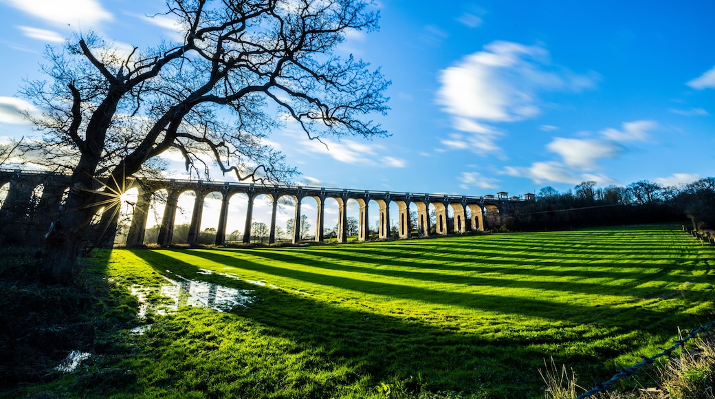 The Ouse Valley Viaduct on an autumn afternoon with clouds streaming overhead and long shadows across the field.