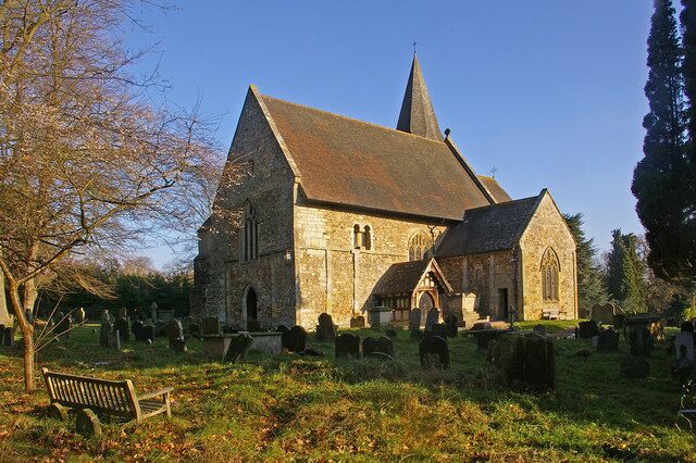 A historic church with a tall spire, surrounded by a cemetery with headstones.