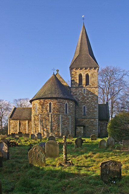 A stone church with two towers and a graveyard in front.