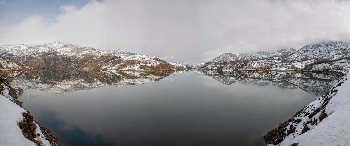 A snow-covered mountain range reflected in a calm lake.